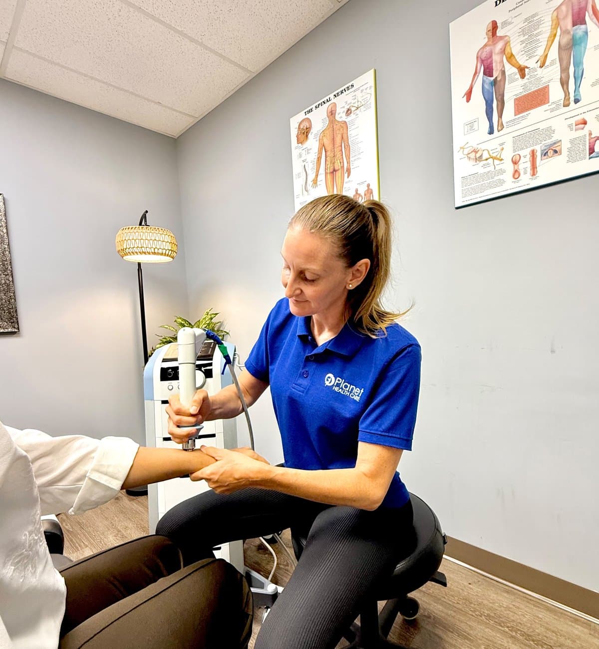 Physiotherapist assessing a patient's shoulder movement in a bright treatment room at Planet Health Care
