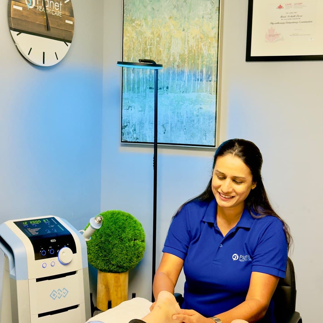 Hiral Desai assessing a patient foot and ankle in a treatment room at Planet Health Care
